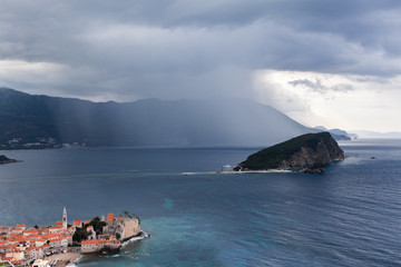 BUDVA, MONTENEGRO - CIRCA JUN, 2016: Rain is over Budvanska riviera and Sveti Nikola island in Adriatic sea. The medieval walled town is on peninsula. Montenegro, Europe