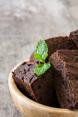 Chocolate brownie portions in bowl on wooden background
