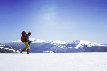 Naklejka na ściany i meble Winter hiking in the mountains on snowshoes with a backpack and
