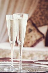 Two champagne glasses with oriental canopy bed at the background