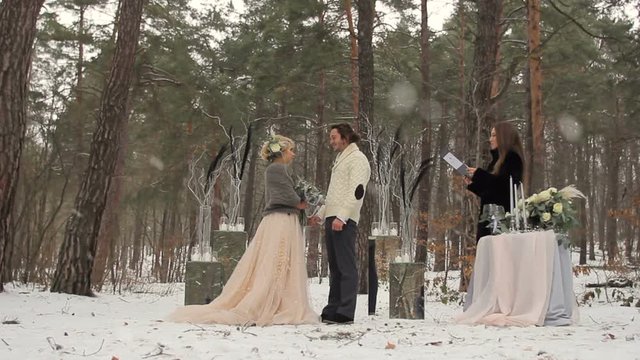 Wedding engagement ceremony of lovely young couple in winter pine forest