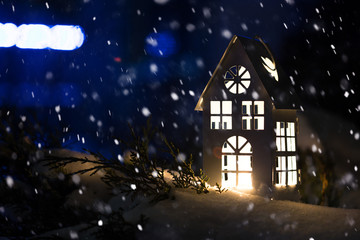 Lantern house with burning candle on snow in the evening
