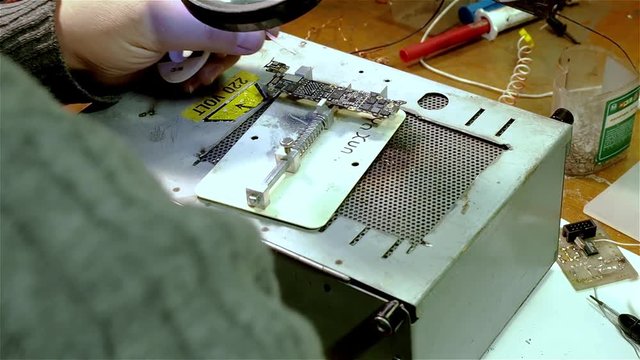 White man repairing broken smartphone iphone in workshop. Preparing motherboard to replace chip