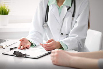 Fototapeta premium Close up of doctor and patient sitting at the desk near the window in hospital