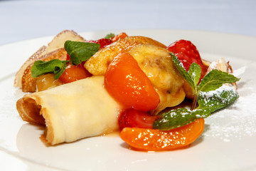 Pancakes sprinkled with powdered sugar fruit and berries are on