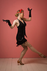 Pretty actress in black retro dress dancing charleston