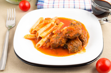 White plate with beef goulash with penne pasta
