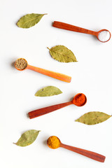 Naklejka premium spices in wooden spoons on white background top view