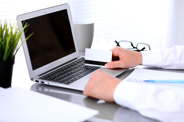 Close up of business woman hands using credit card and laptop computer