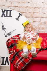 The child, a little girl sitting near a well-dressed Christmas tree and unwraps a gift.