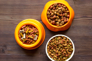 dry dog food in bowl on wooden background top view