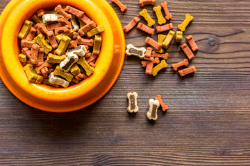 dry dog food in bowl on wooden background top view