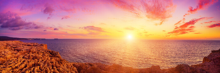 Beautiful colorful sunset at the sea with dramatic clouds and sun shining. Panoramic view. Beauty...