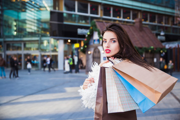 Fototapeta premium Portrait of beautiful young brunette woman with shopping bags outdoors