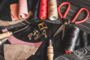 Instruments in leather shop on dark wooden background top view