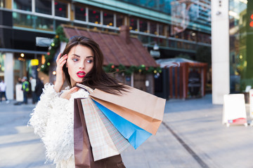 Portrait of beautiful young brunette woman with shopping bags outdoors