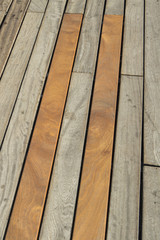 Detail of wooden pedestrian walkway with some tiles in different colors