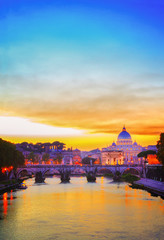 Obraz premium St. Peter's cathedral over bridge and river in Rome at orange sunset, Italy