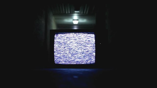 Tv sitting in hallway that is dark and a little scary.