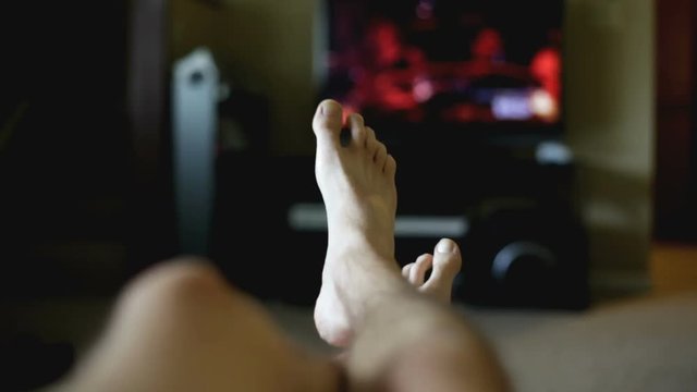 Man's Feet Sitting On Recliner Watching Television With Dancing Nervous Feet.