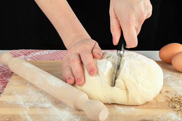 Woman kneading and cutting dough on wooden kitchen table
