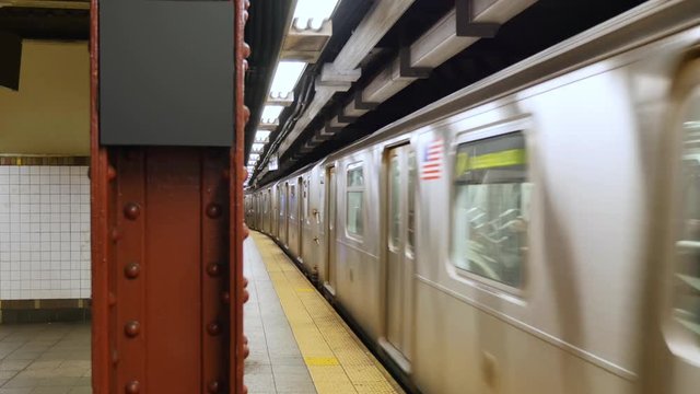 A Manhattan subway train leaves the platform. Blank sign on pillar for customization.  	