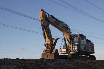 Excavator Parked Under Power Lines on a Construction Site