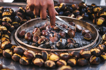 Man preparing roasted chestnuts, cooking outdoors. Street food i
