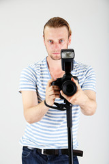 Obraz premium Handsome photographer with camera on monopod, on gray background