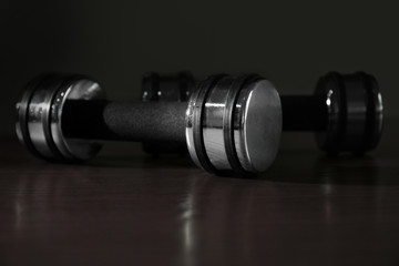 Dumbbells on wooden surface against dark background