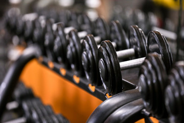 Rack with different dumbbells in gym, close up