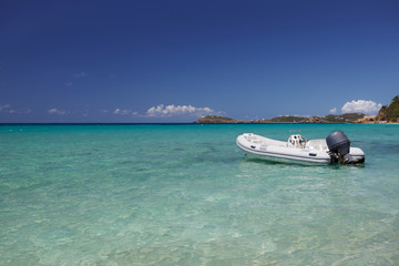 Fototapeta na wymiar Dinghy with outboard motor anchored in a tropical bay