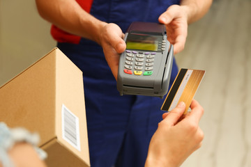 Young woman paying for parcel received from courier, closeup