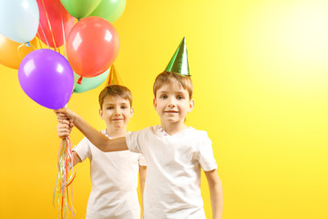 Cute birthday boys with colorful balloons on yellow background