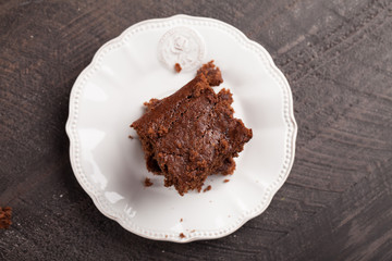 Walnut brownie cake stacked on white plate on dark wooden background top view