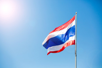 waving Thai flag of Thailand with blue sky background.