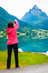 Fototapeta na wymiar Tourist taking photo at norwegian fjord lake