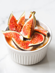 Yogurt with pieces of fig and honey in a white bowl on white background
