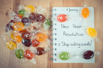 Vintage photo, New years resolutions written in notebook and colorful candies