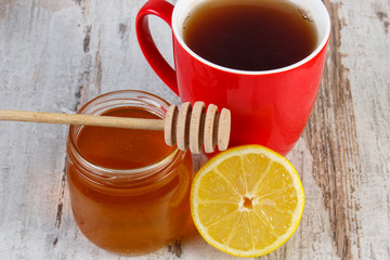 Fresh lemon with honey and cup of tea on wooden table, healthy nutrition