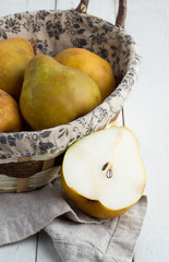 yellow pears in a basket on a wooden background