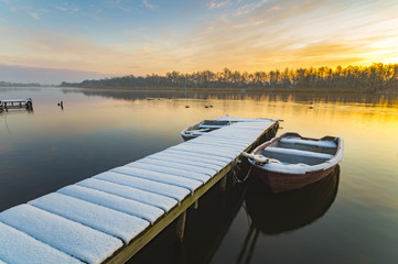 Obraz premium boat moored to the snow-covered bridge over the lake in winter m