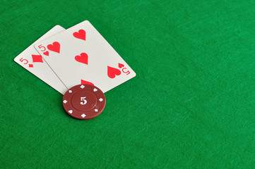 Two cards with a poker chip with the value of five 