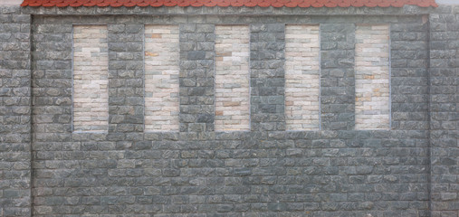 Detail of modern stone wall with red tiled roof
