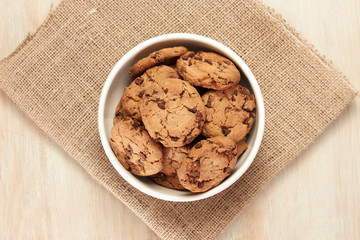 Bowl of chocolate chips cookies on burlap with copyspace