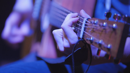 Musician in night club guitarist plays acoustic guitar, extremely close up