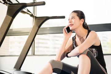 Fototapeta na wymiar asian woman rest sitting treadmill use smartphone and smartwatch