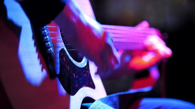 Musician in night club - guitarist plays blues acoustic guitar, extremely close up