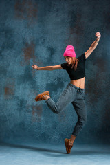 Naklejka na ściany i meble Young girl break dancing on wall background.
