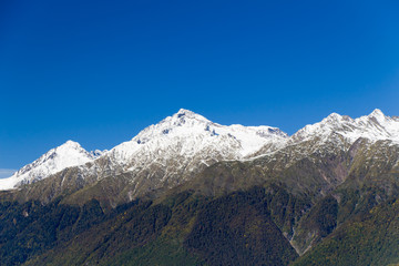 The tops of the mountains covered with snow. The slopes are thic